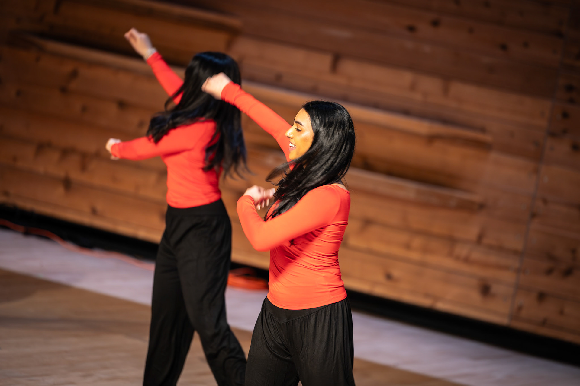 Two dancers in red performing beneath warm stage lights