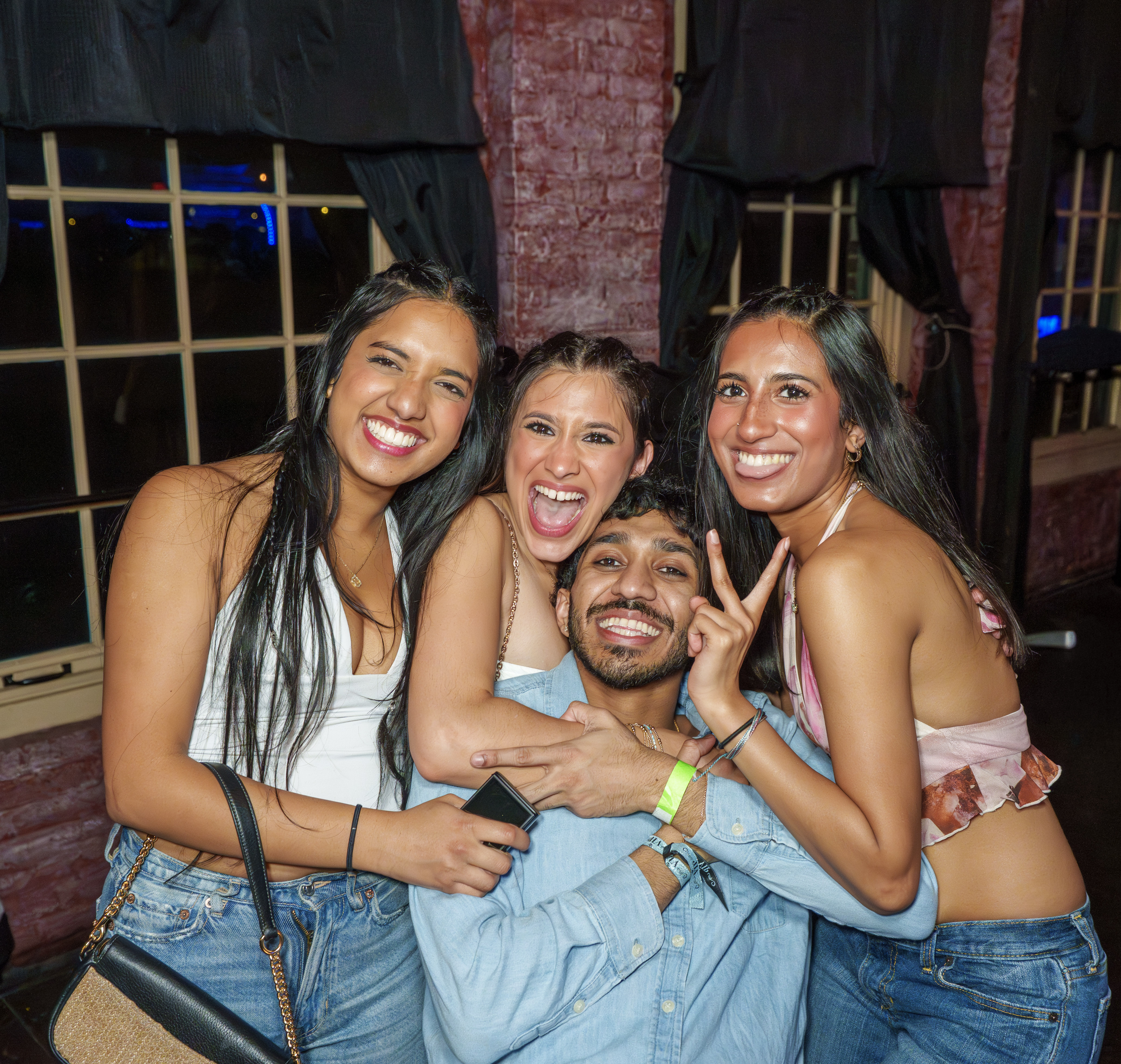 Four friends laughing and posing together at a nightlife event
