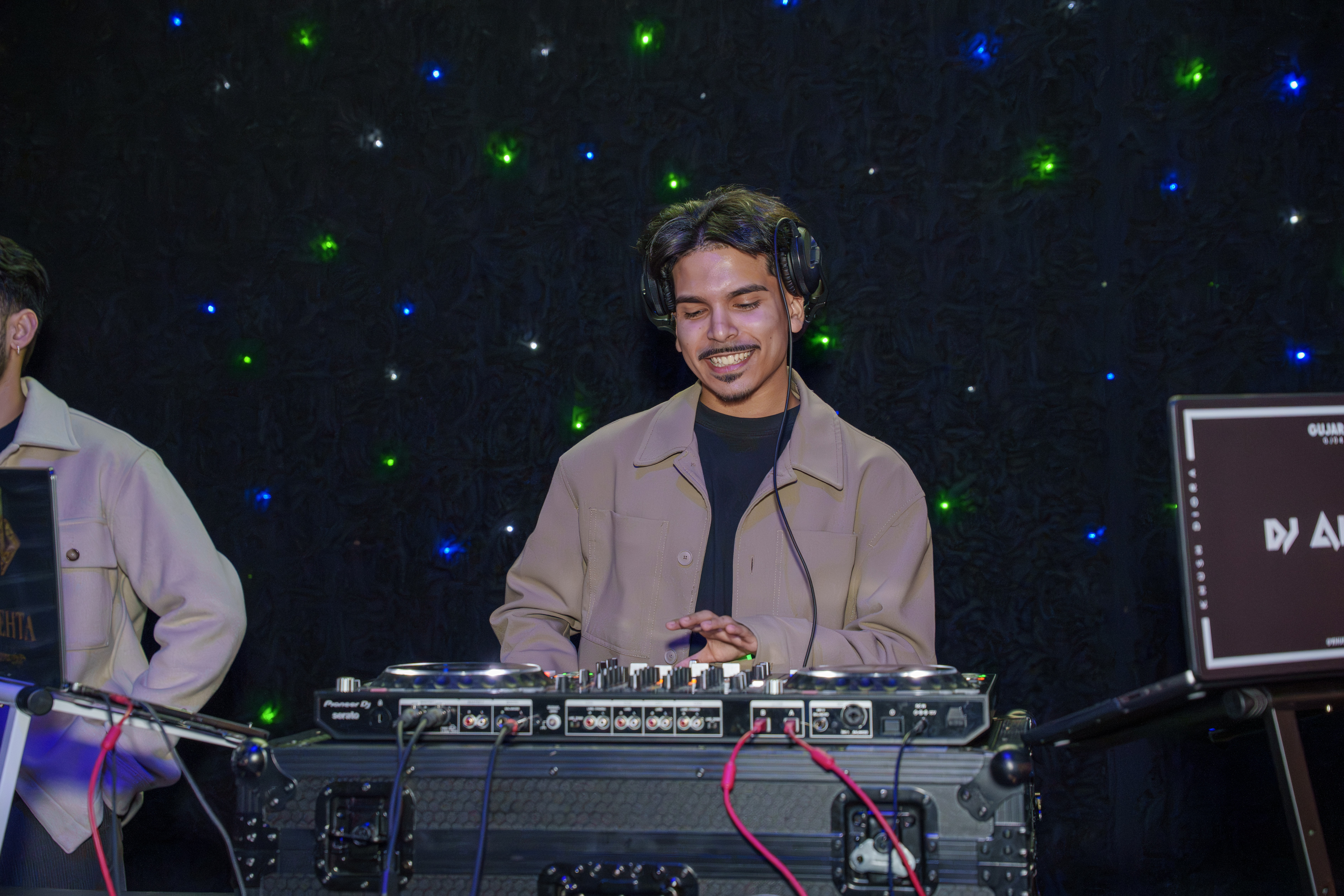 Smiling DJ mixing music in front of a star-lit backdrop