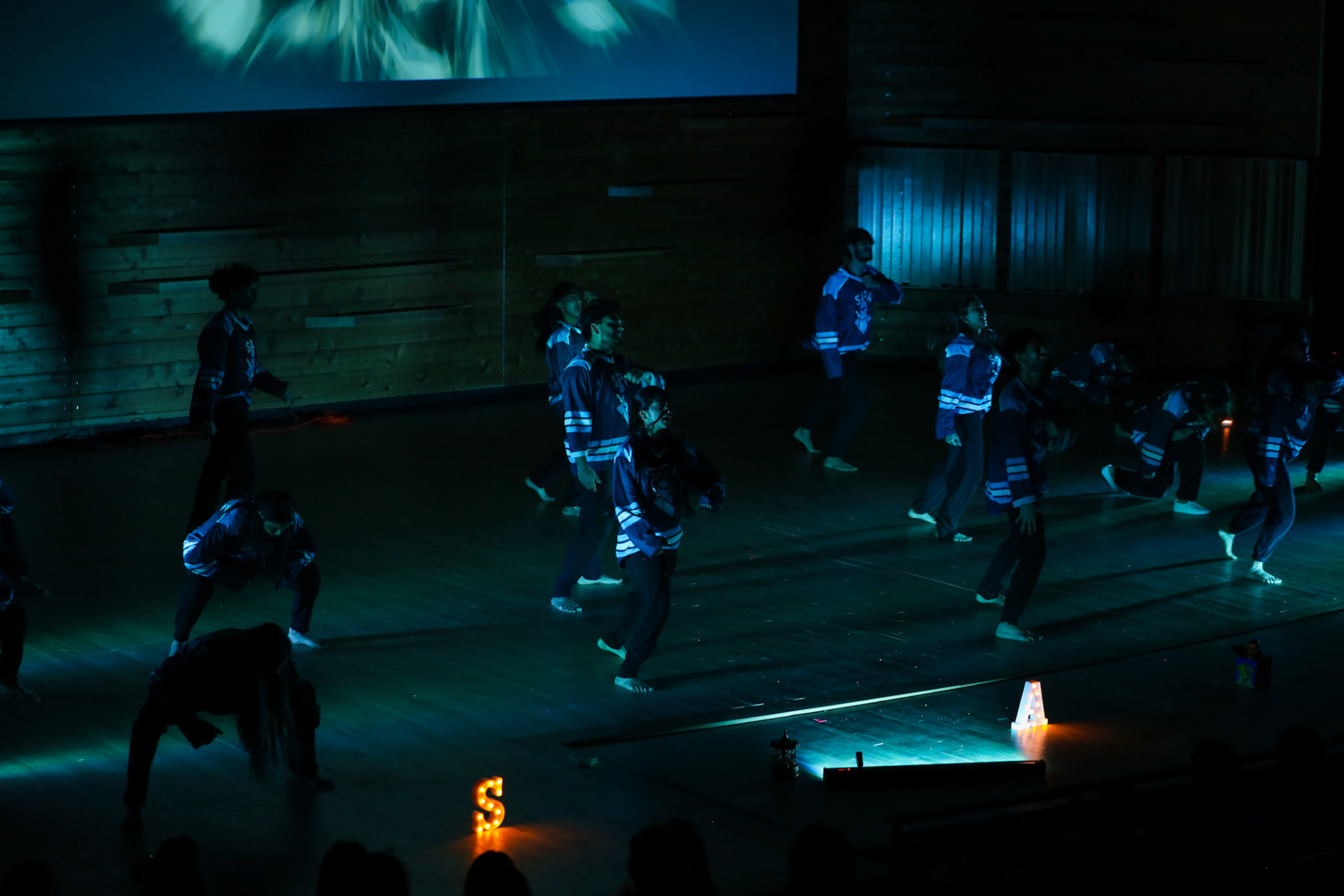 Dance ensemble performing under deep blue stage lighting