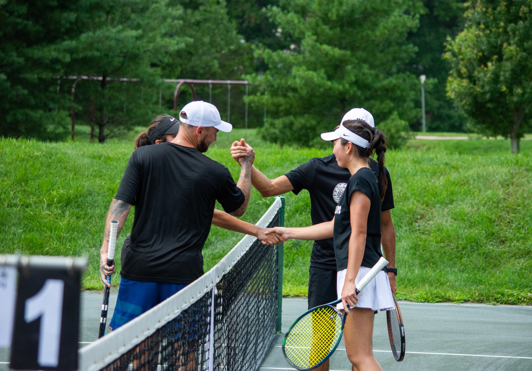 Tournament players shaking hands across the net after a tennis match