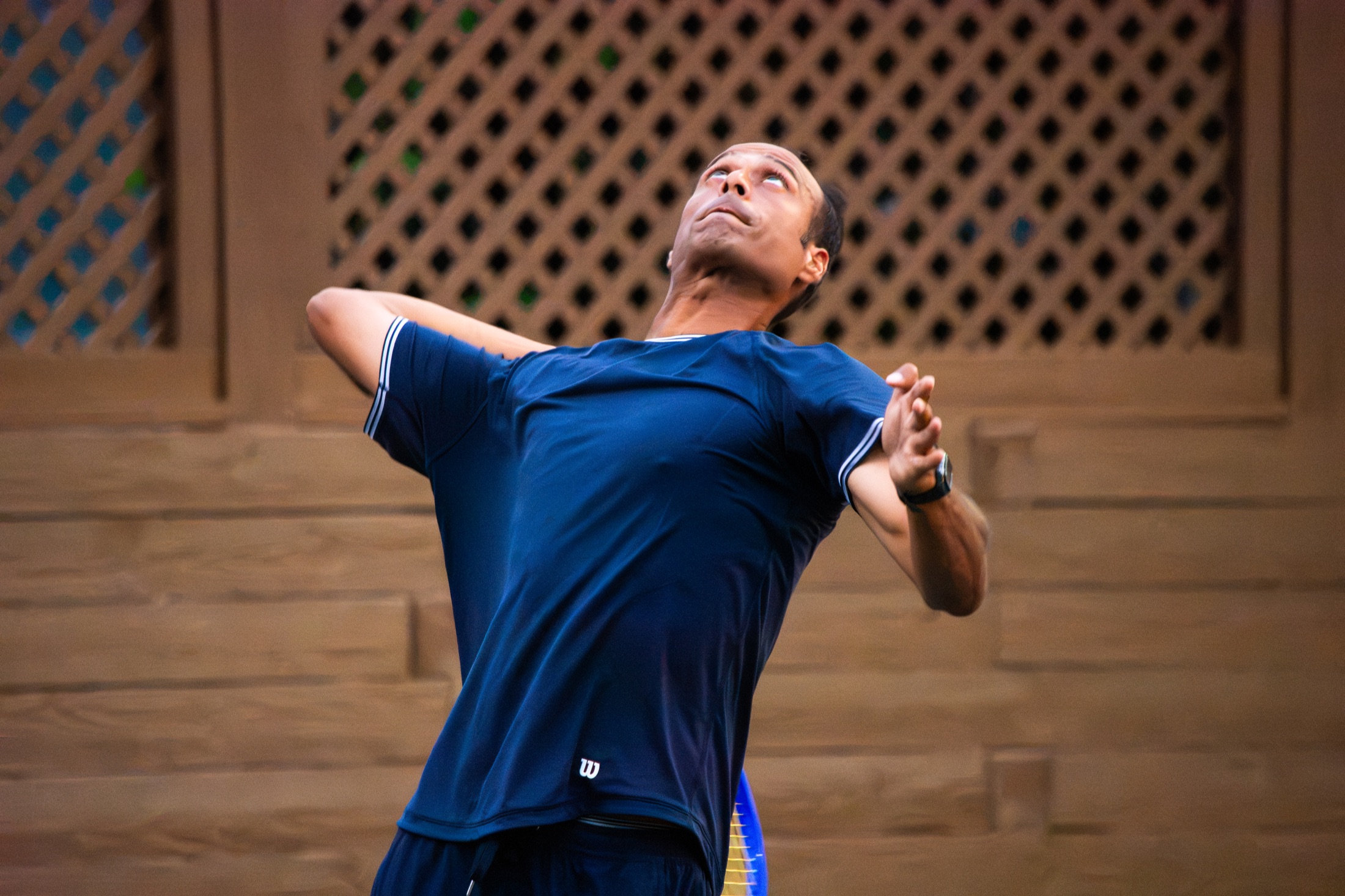 Tennis player in navy coiling to serve during a tournament match