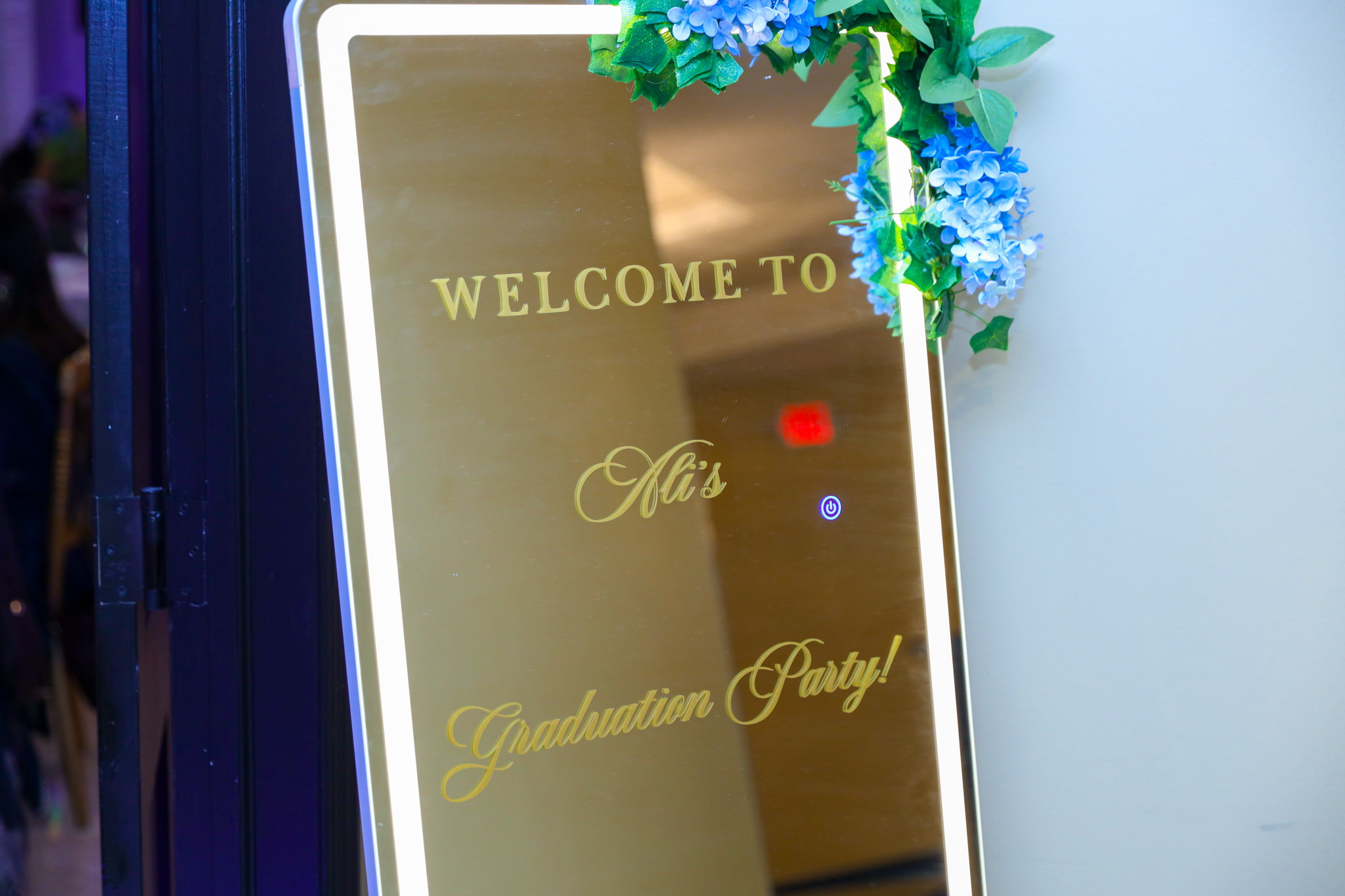 Illuminated welcome mirror decorated with flowers for a graduation party