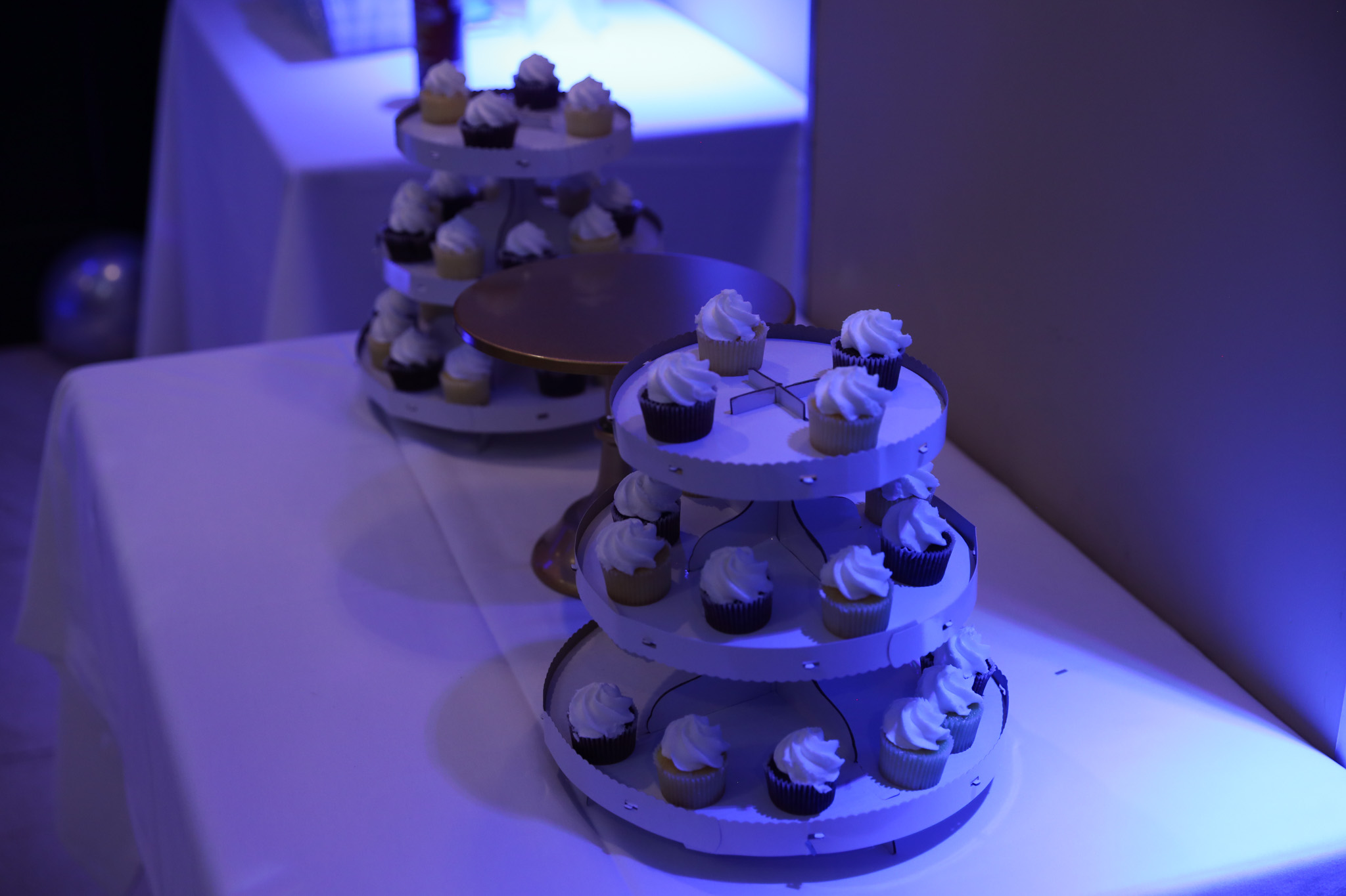 Tiered cupcake displays under blue party lighting