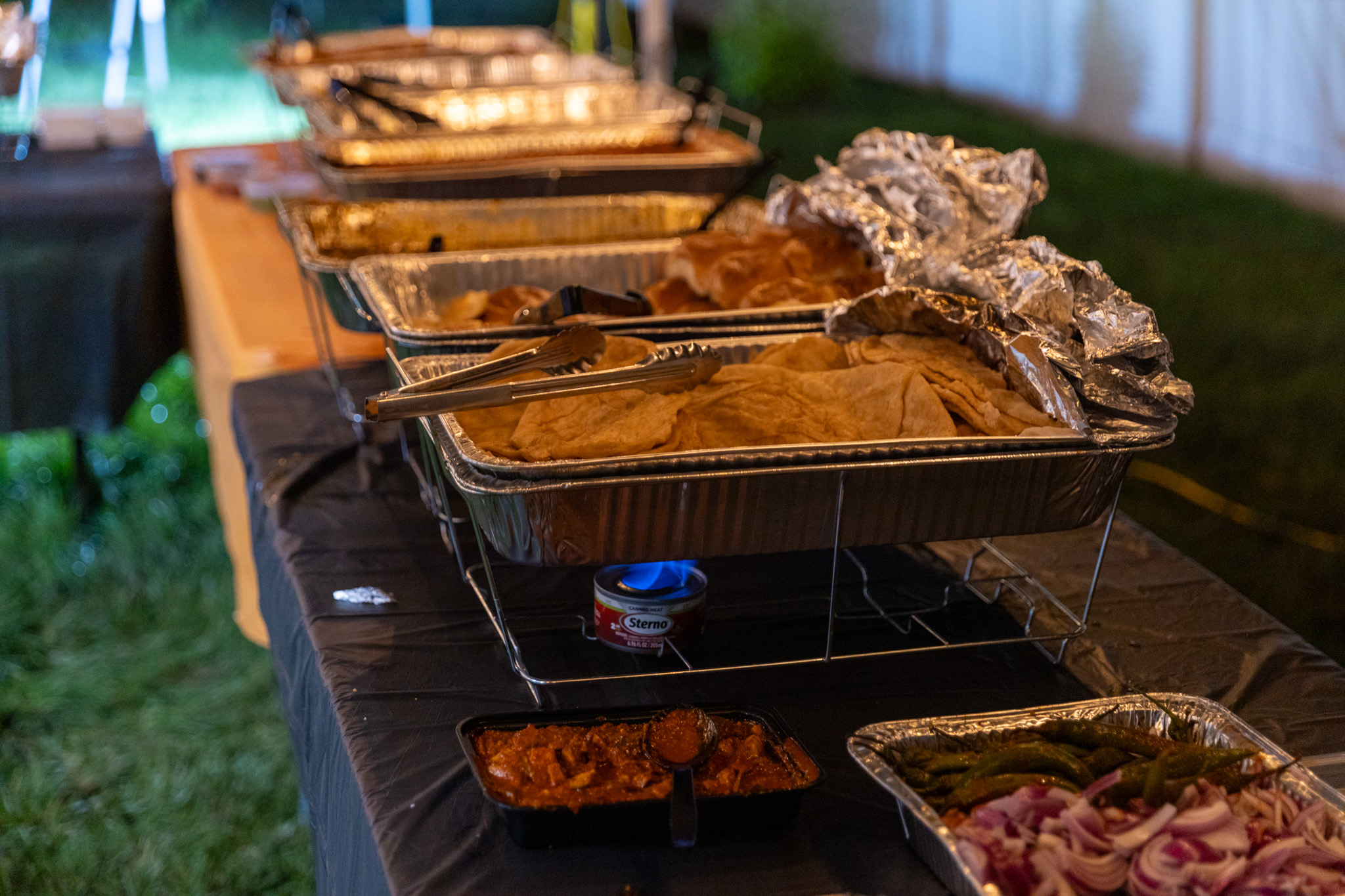 Outdoor graduation buffet kept warm over small flames