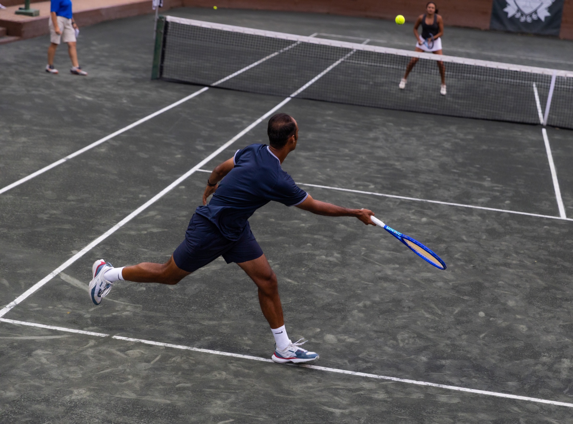 Tennis player lunging for a volley during a mixed doubles match